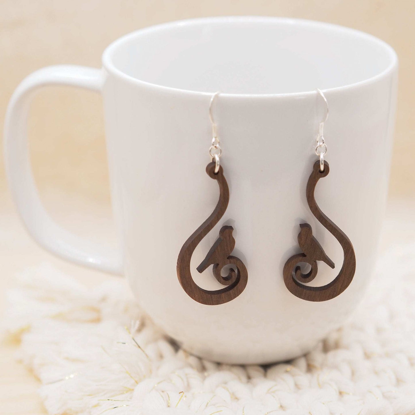 Swirling bird drop earrings hung on delicate sterling silver hooks